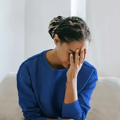  A woman with her hand on her face wanting help from a drug rehab.